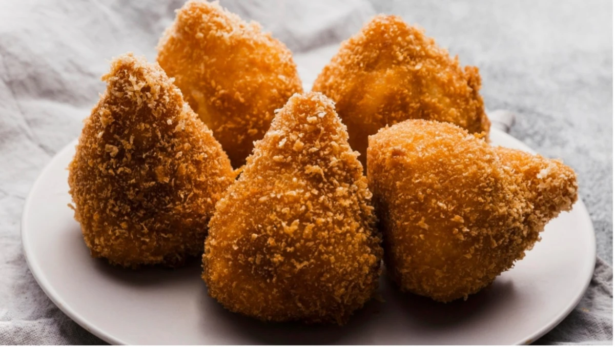 Arancini w kształcie stożków leżą na białym talerzu